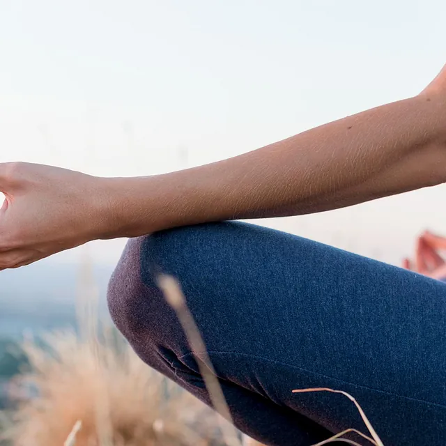 Nærbilde av yoga håndposisjon, naturen i uskarp bakgrunn.
