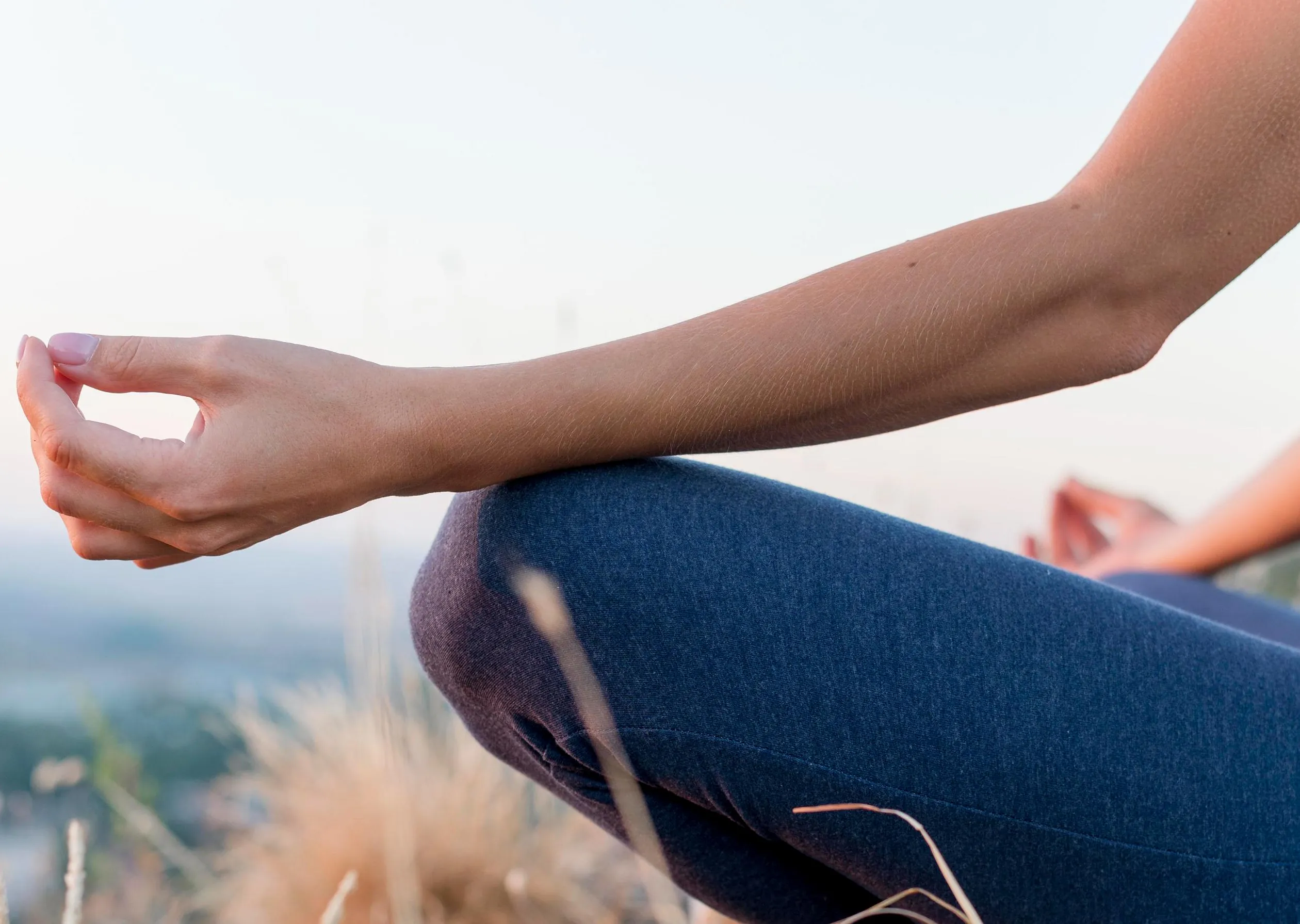 Nærbilde av yoga håndposisjon, naturen i uskarp bakgrunn.